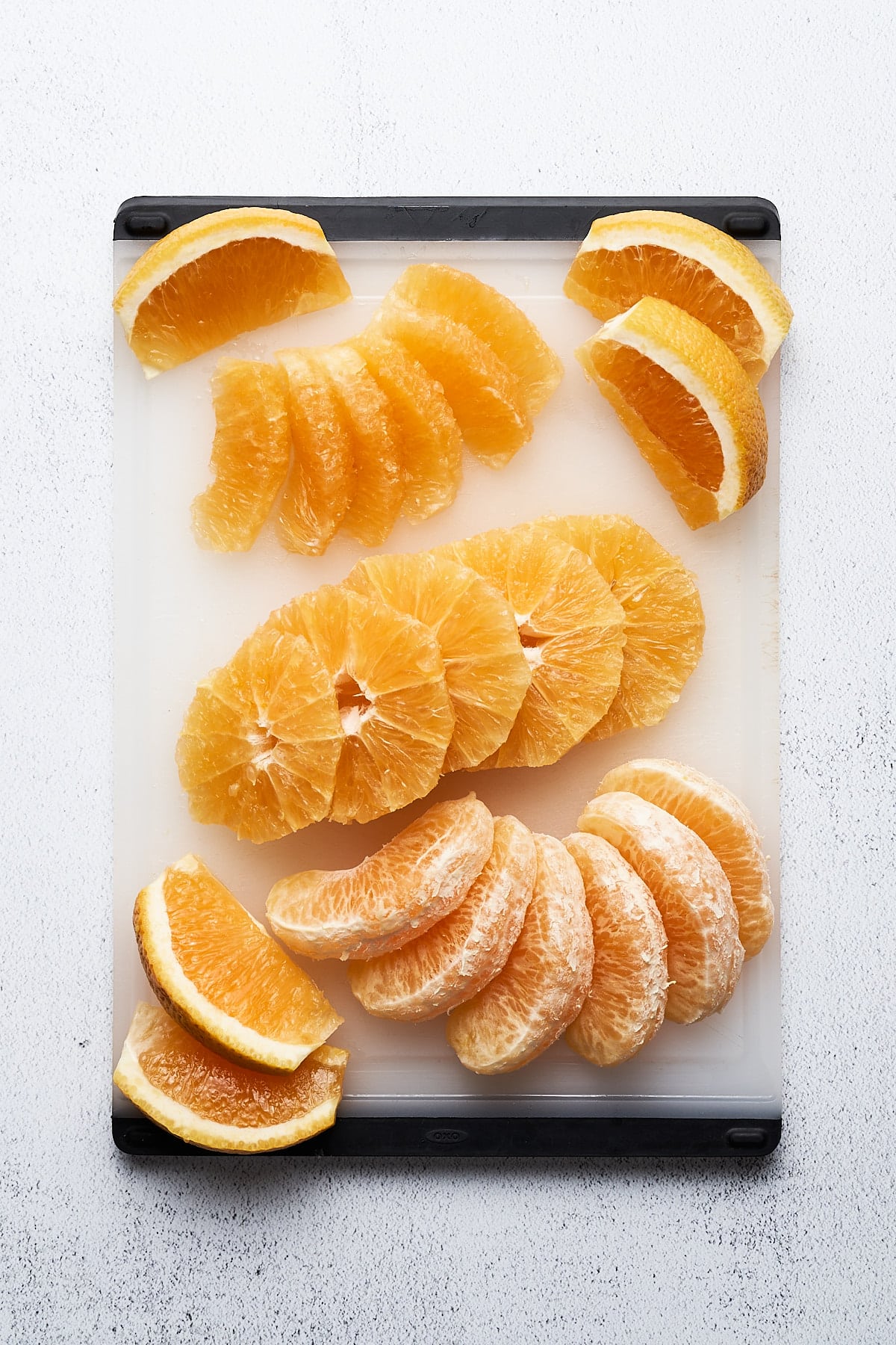 Different cuts of oranges on a cutting board.