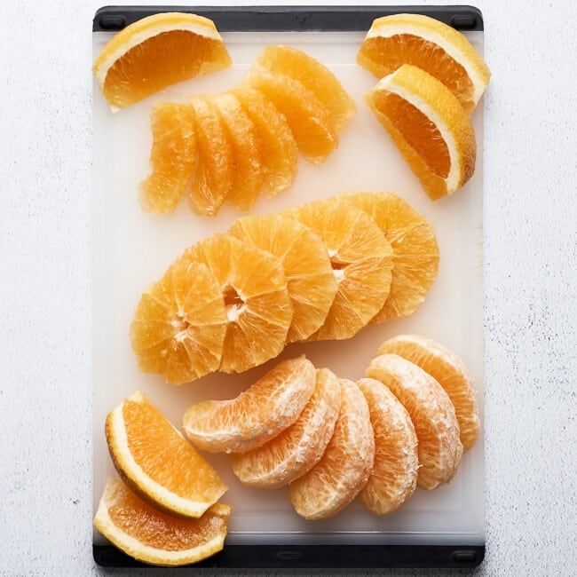 Cut up oranges on a cutting board.