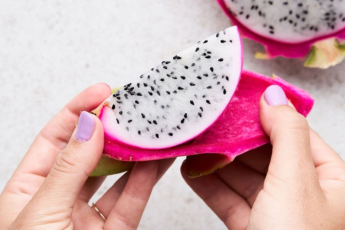 Remove Skin: Either scoop out fruit with a spoon by running a spoon along the edge of each half where the flesh meets the peel, OR peel. To peel, cut the dragon fruit halves lengthwise into quarters. Using your hands, lift the flesh away from the peel.