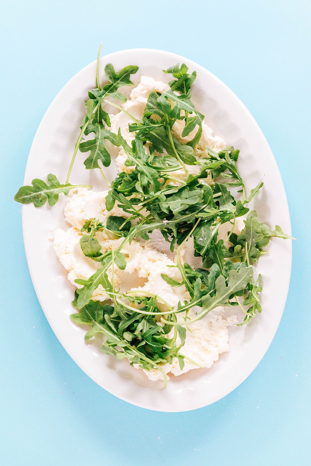 A platter with whipped feta and arugula.