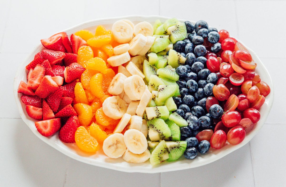 Diced fruits in rainbow order on a large white oval platter.