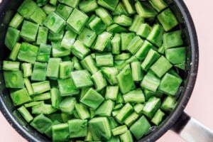 A black pot filled with chopped green nopales (cactus paddles) pieces submerged in water, showing how to cook nopales before adding them to your favorite dishes.