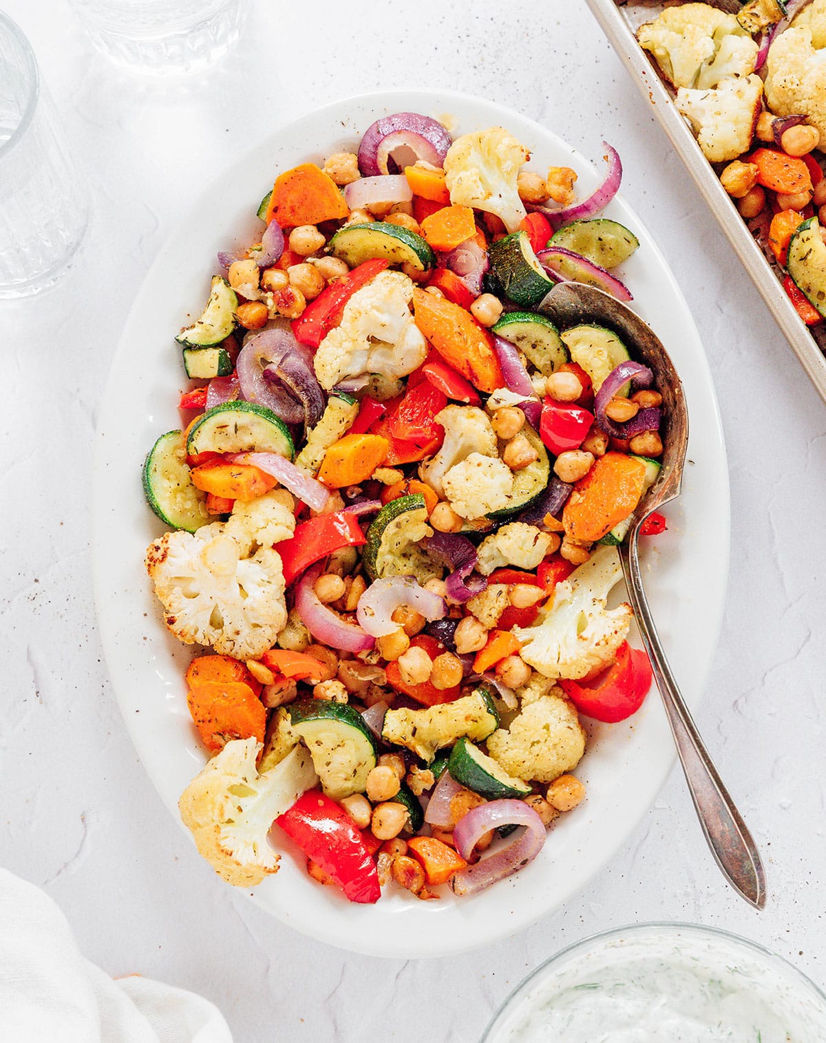 A serving bowl of roasted Mediterranean veggies including cauliflower and zucchini.