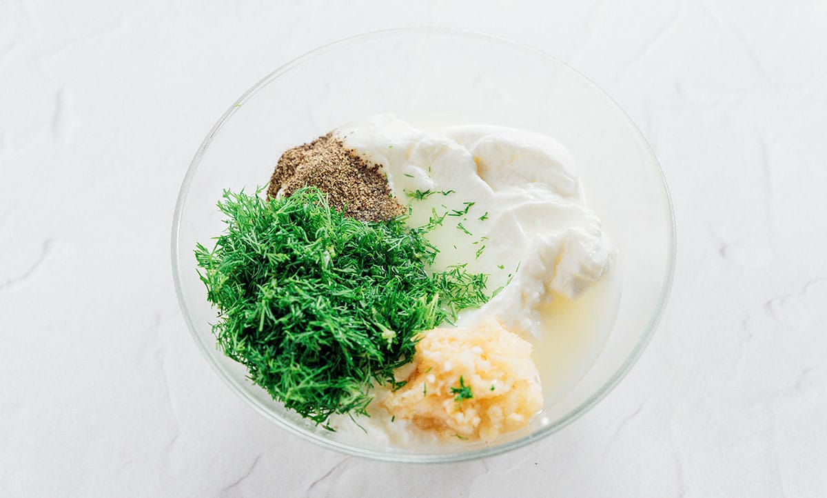 Fresh herbs with garlic and yogurt in a small glass bowl.