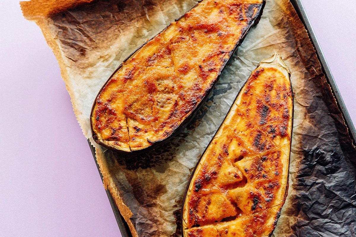 Roasted miso eggplant halves on a parchment lined baking sheet.
