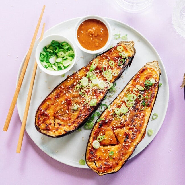 Miso glazed eggplant on a white plate with chopsticks.