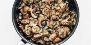 A skillet filled with sautéed mushrooms, onions, and herbs, cooked until browned and mixed together—the perfect filling for a classic beet wellington.