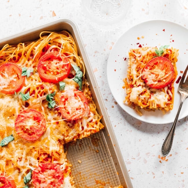 Spaghetti pizza on a serving plate.