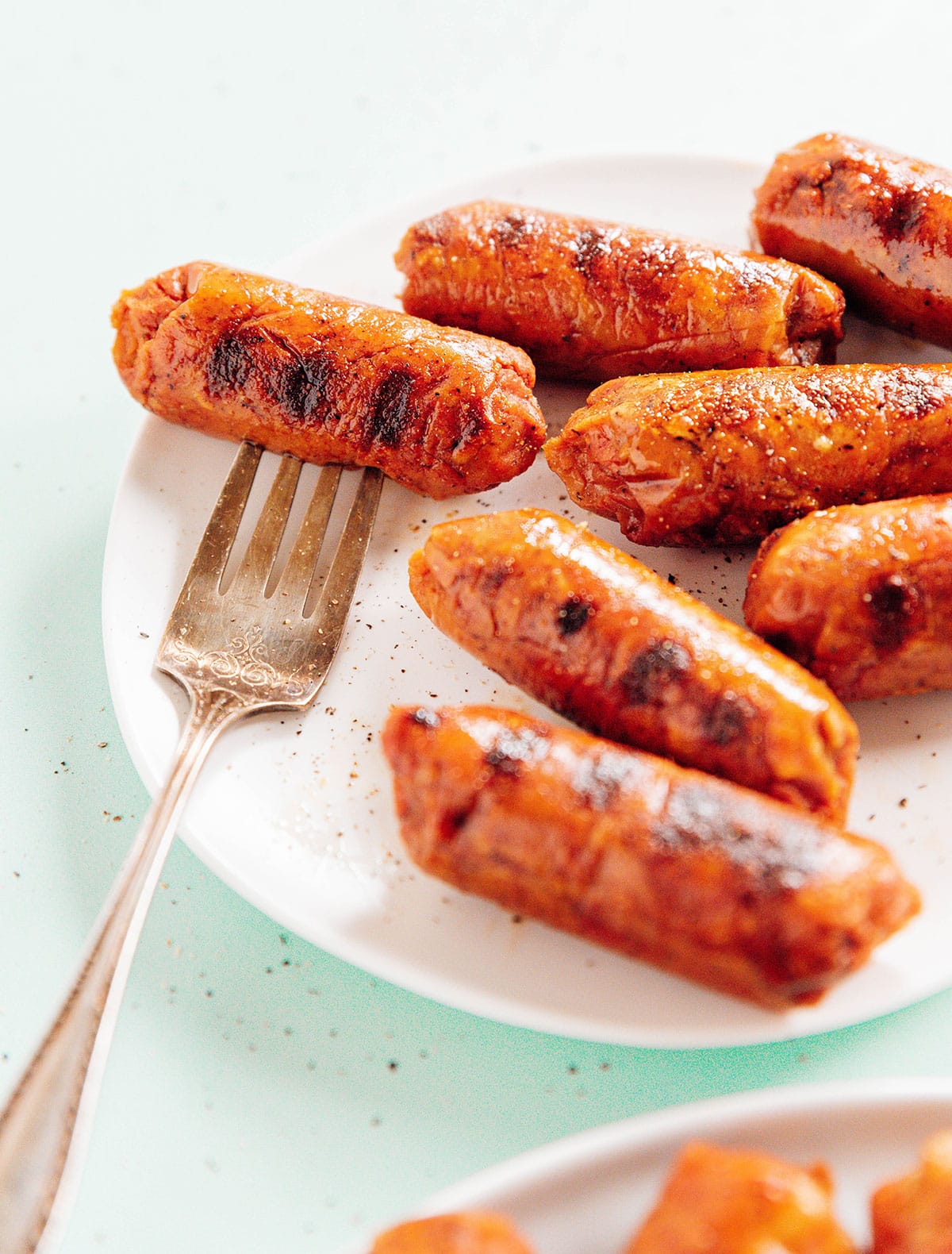 A fork on a plate of plant-based sausage links.