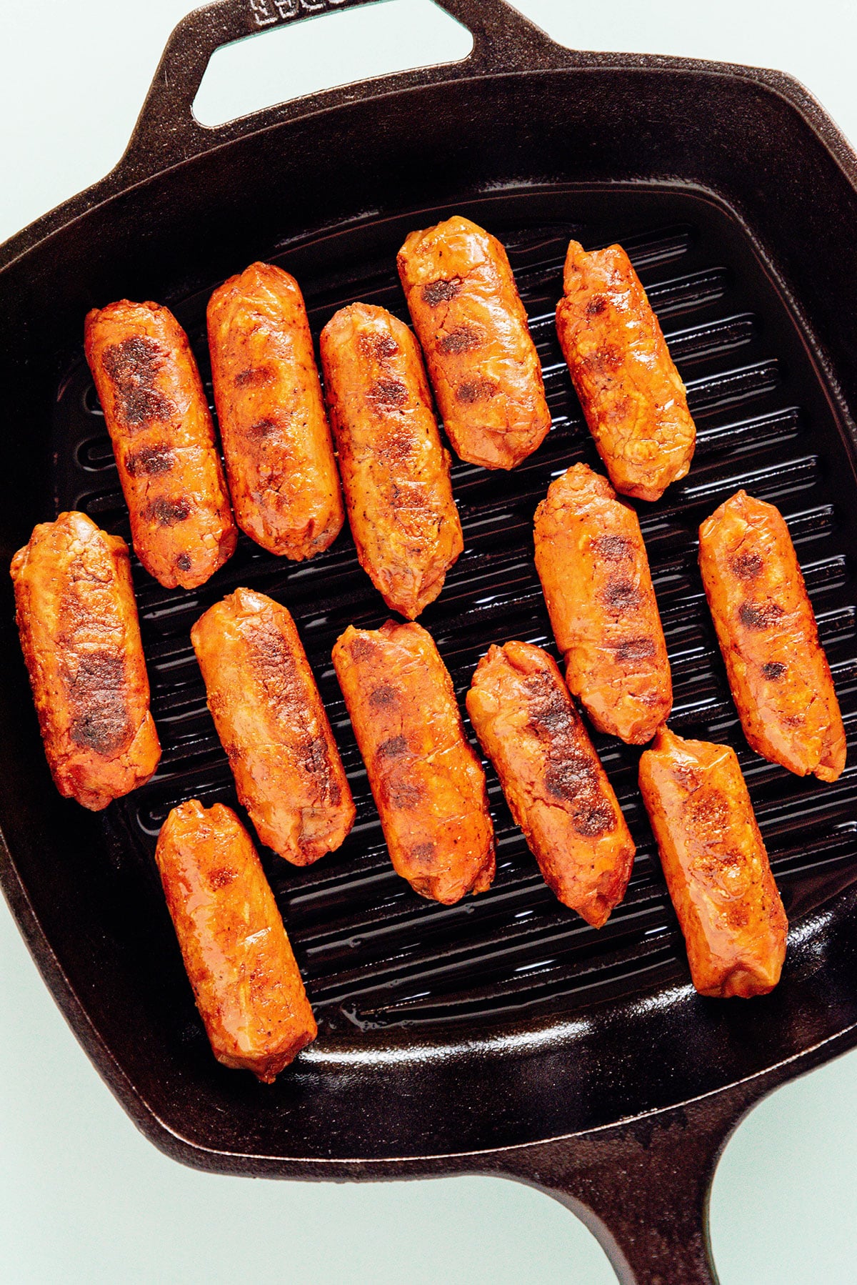 Steamed vegan sausages on a cast iron grill pan.
