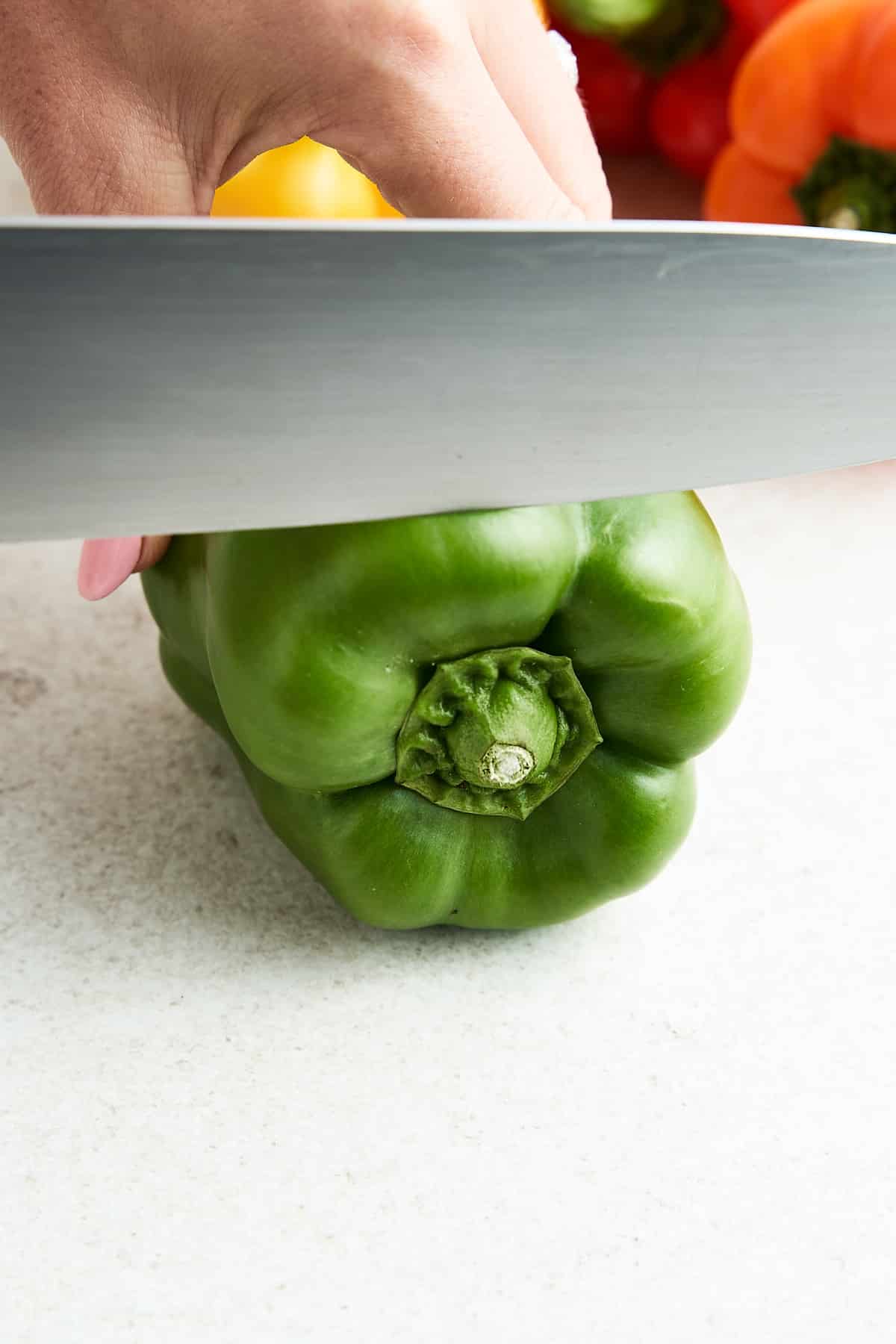 Trimming the top off a bell pepper.
