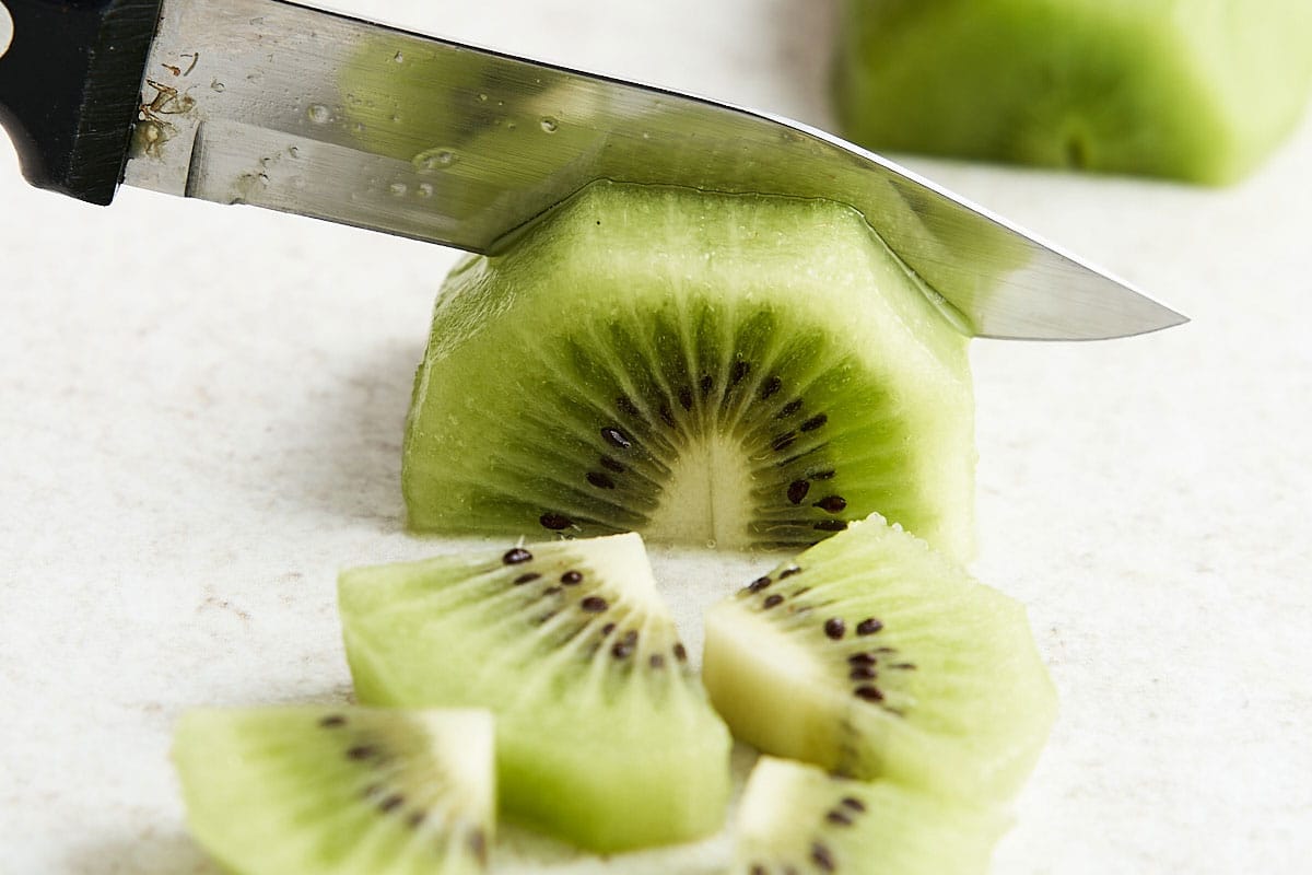 Once the kiwi is peeled, stand it upright. Slice it in half lengthwise, then lay each half on its side and slice it again so you have quarters. Make crosswise cuts down each one as thickly or as thinly as you'd prefer.