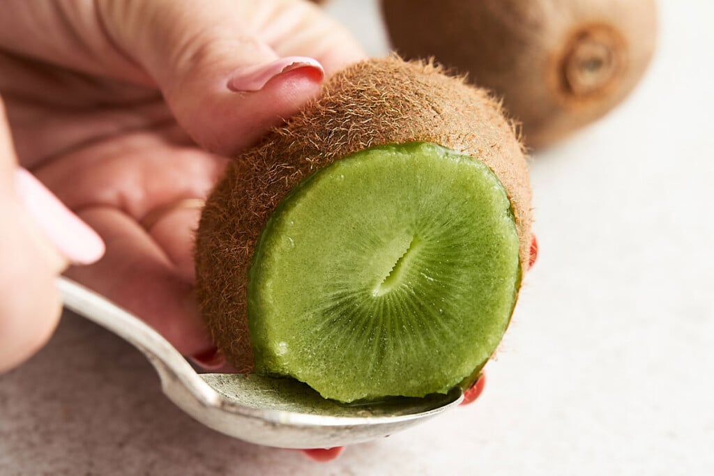 Peeling Option 3: The last way to peel a kiwi is with a spoon. Once you've trimmed away both ends, insert a spoon where the skin and the flesh meet. Pushing the spoon against the skin, rotate the kiwi until the skin pulls away, then slide the inside out.