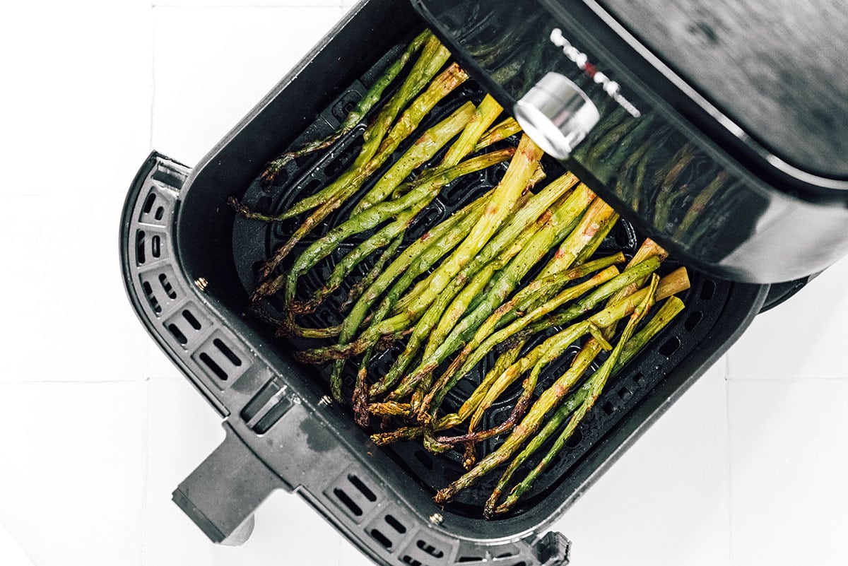 Asparagus spears in the basket of an air fryer.