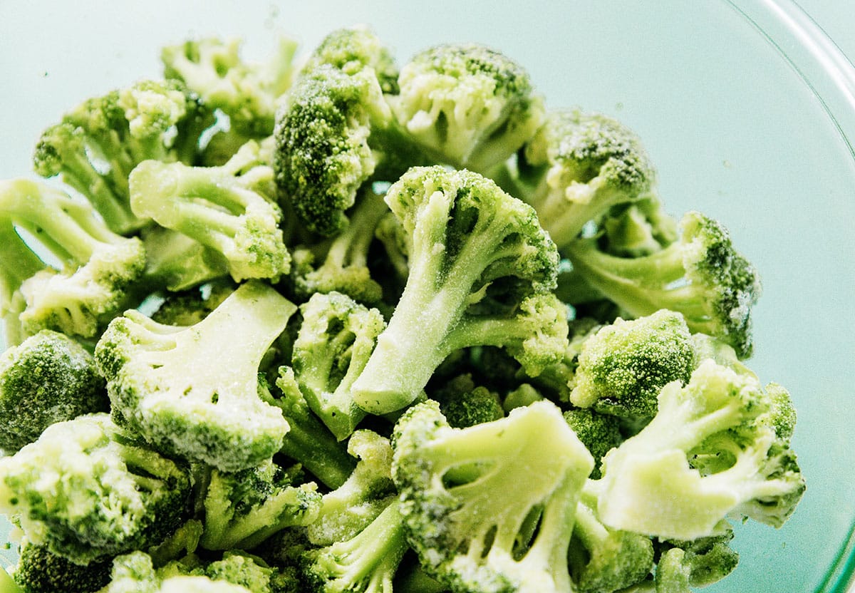Frozen broccoli florets in a glass mixing bowl.
