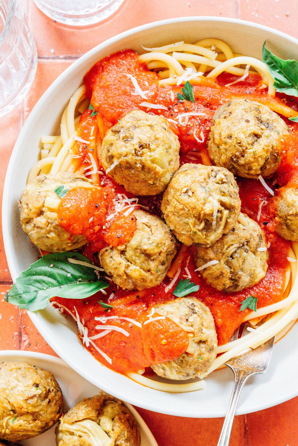 Baked vegetarian meatballs on top of a bowl of spaghetti.