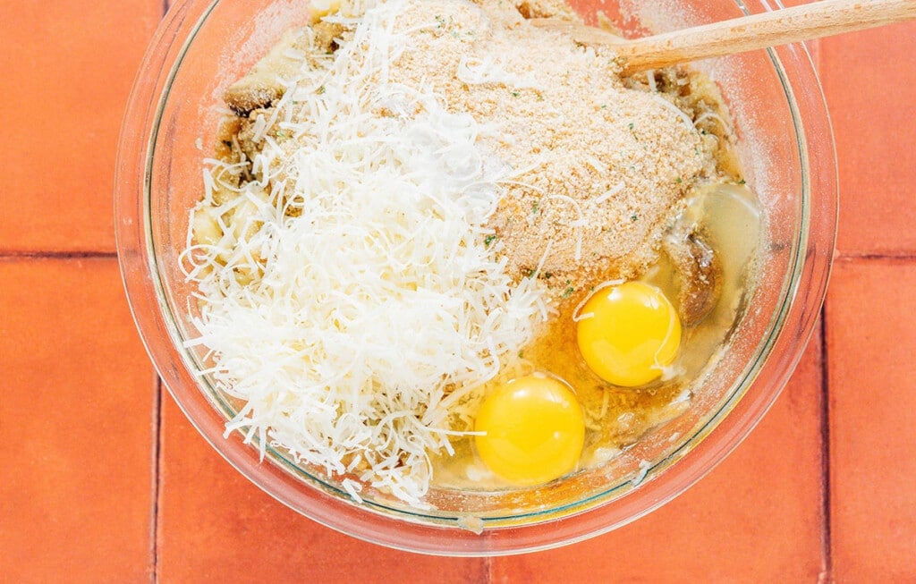 Mixing eggplant with cheese, breadcrumbs, and eggs.