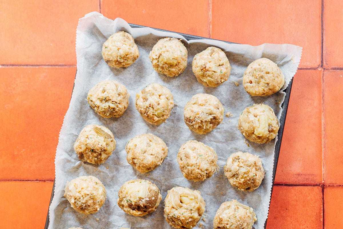 Eggplant meatballs formed into balls on a parchment lined baking sheet.