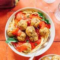 Eggplant meatballs in a bowl with spaghetti and marinara.