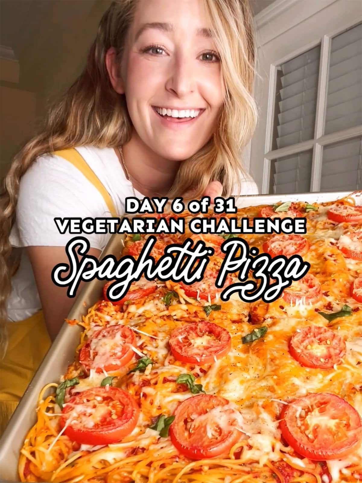 Girl holding pan of spaghetti pizza.