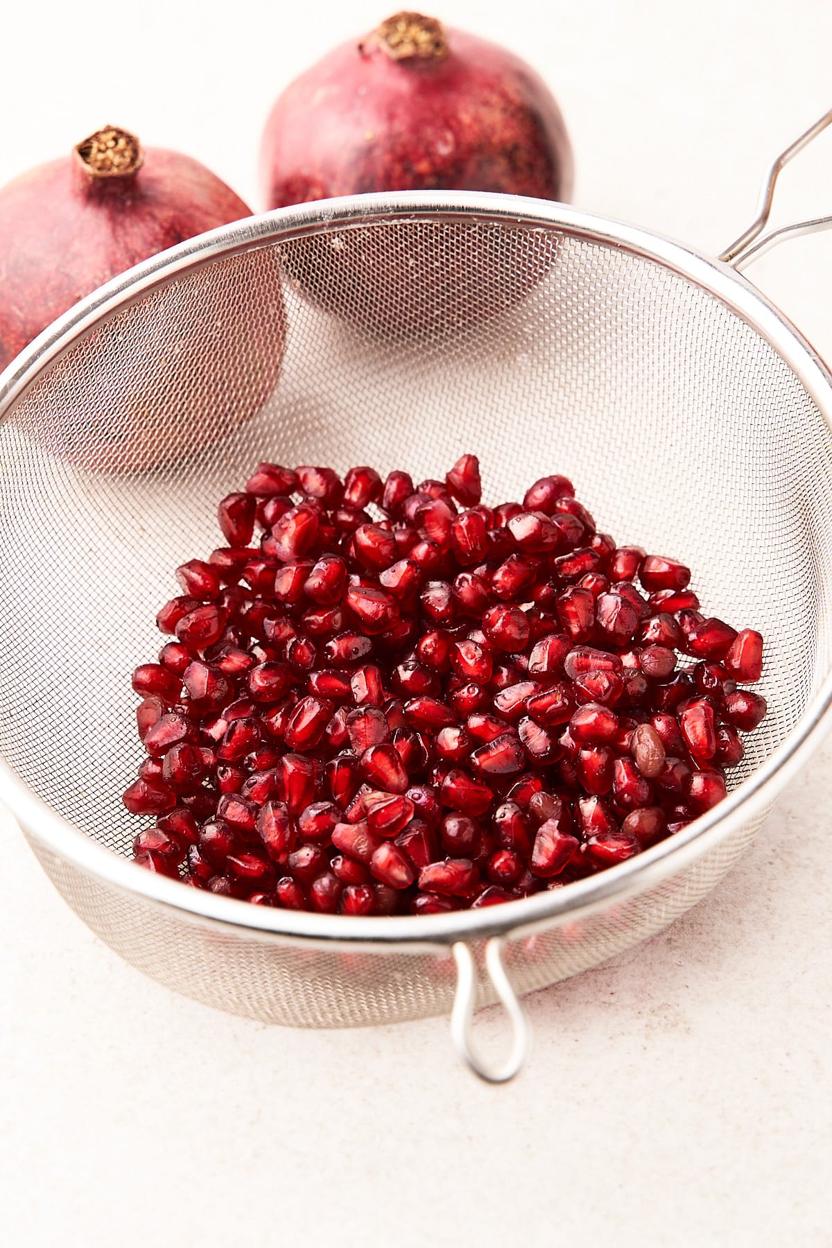 Pomegranate arils in a strainer.