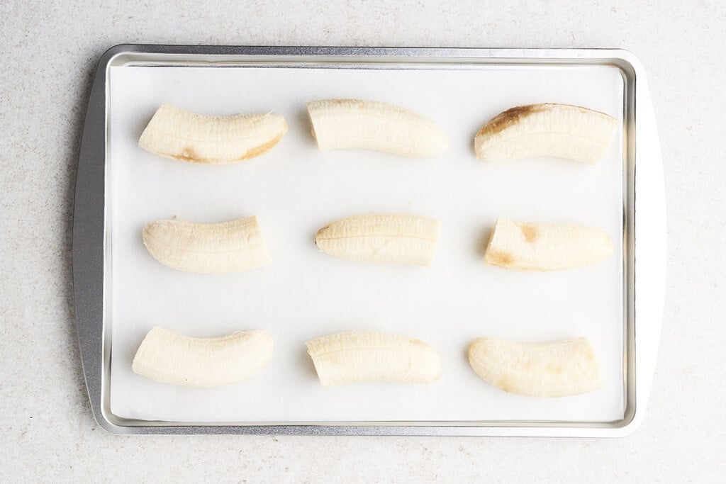 Freezing bananas into chunks on a parchment lined baking sheet.