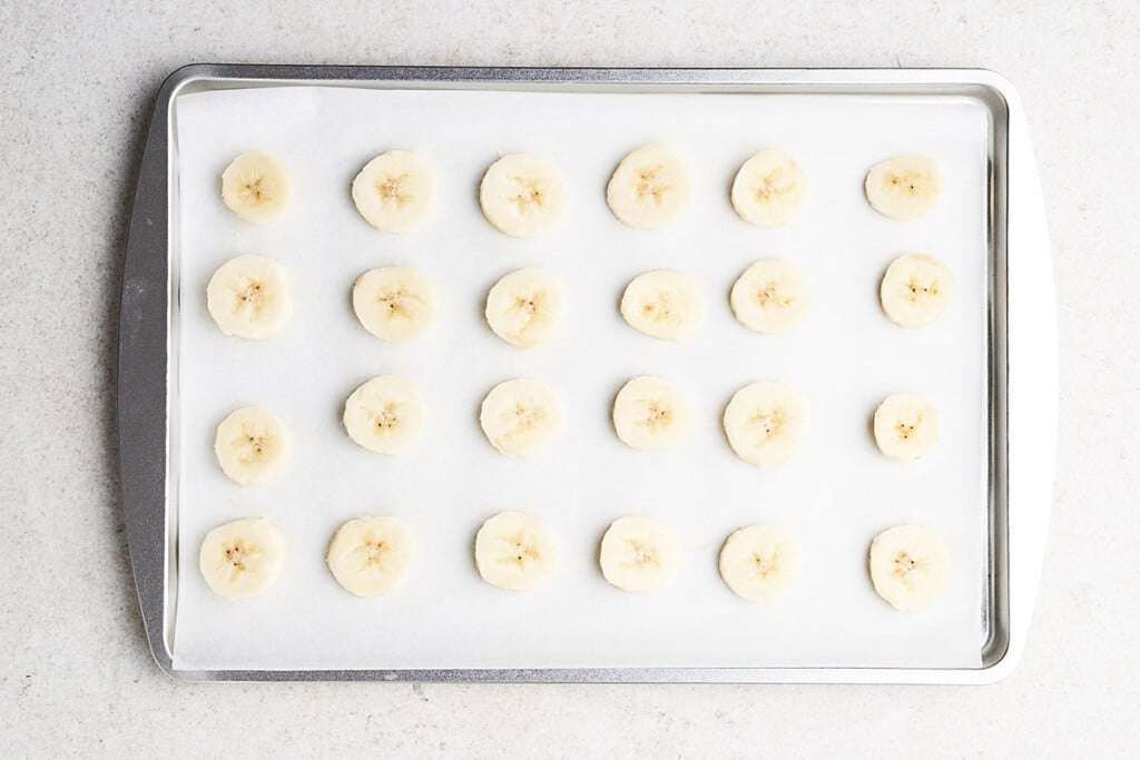 Freezing bananas into slices on a parchment lined baking sheet.