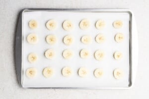 Freezing bananas into slices on a parchment lined baking sheet.