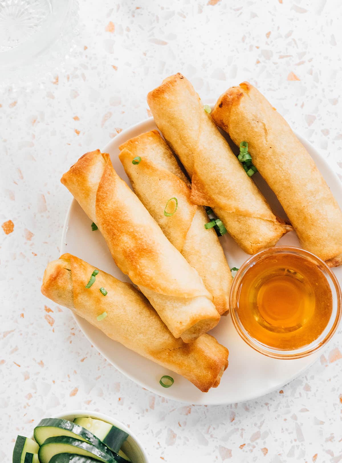 Fried frozen spring rolls on a plate with a dipping sauce on the side.