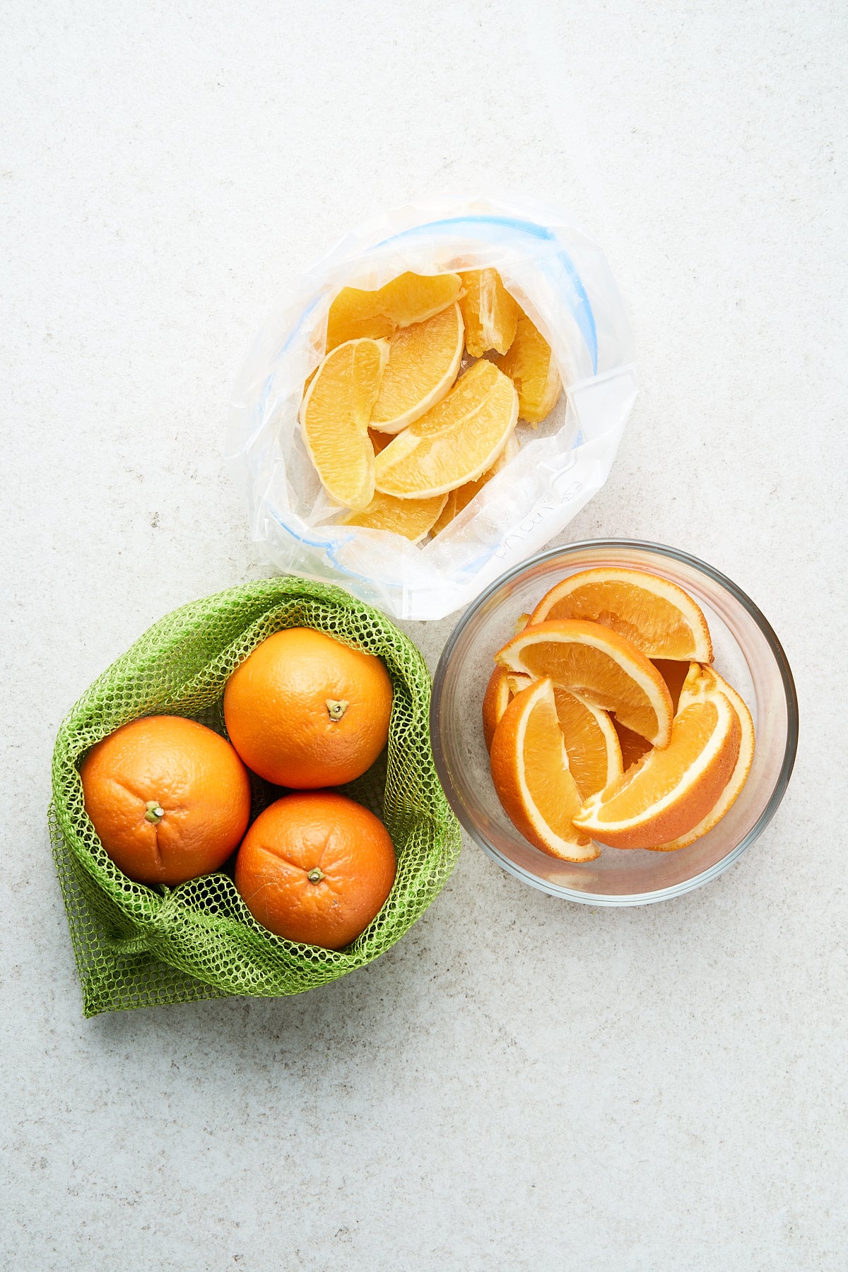 Oranges in a mesh bag, glass container, and plastic bag.