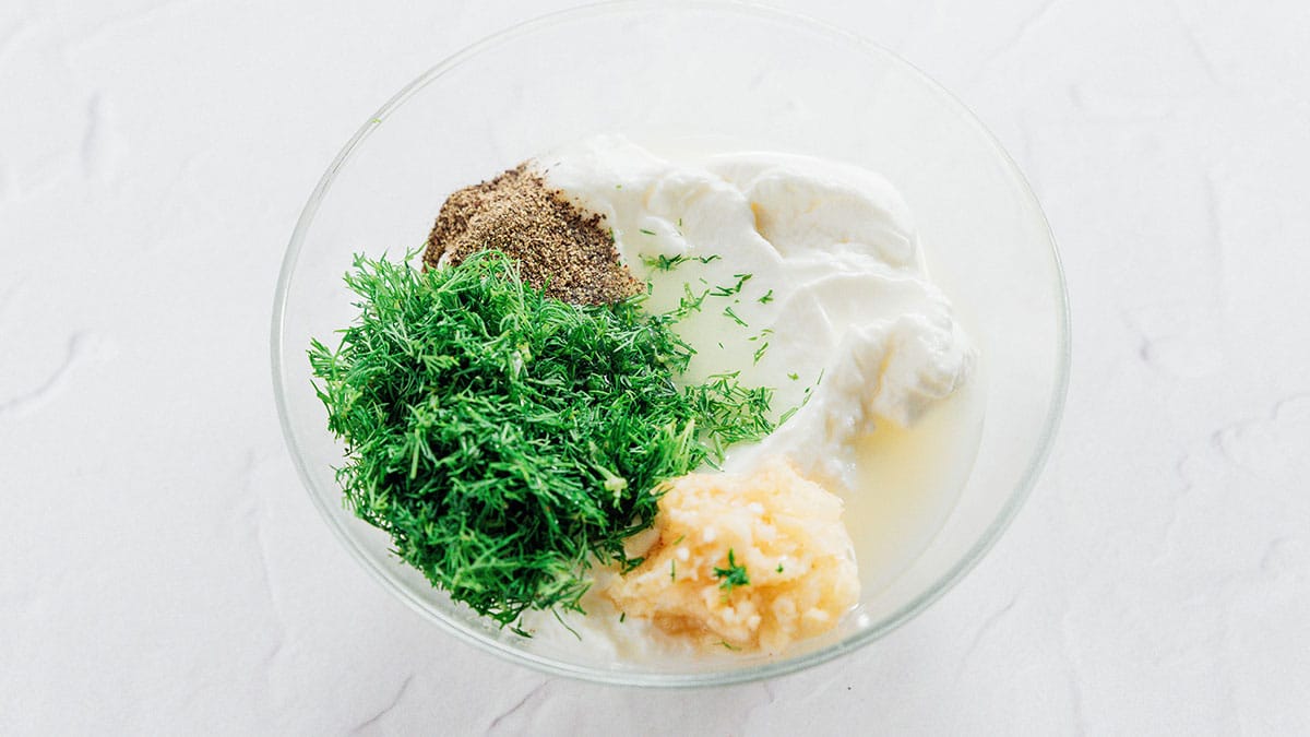 Dill yogurt sauce in a glass bowl.