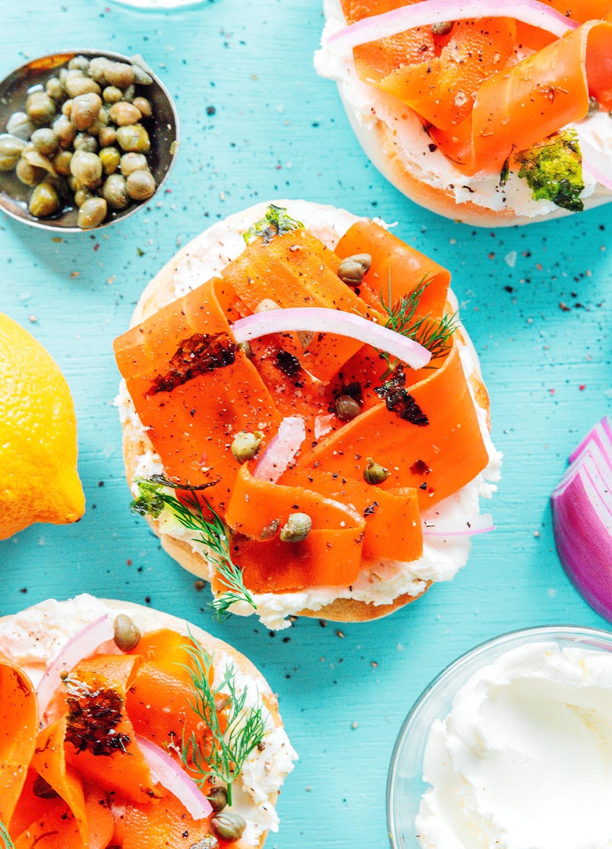 Bagel with cream cheese, carrot lox, capers, and red onions.
