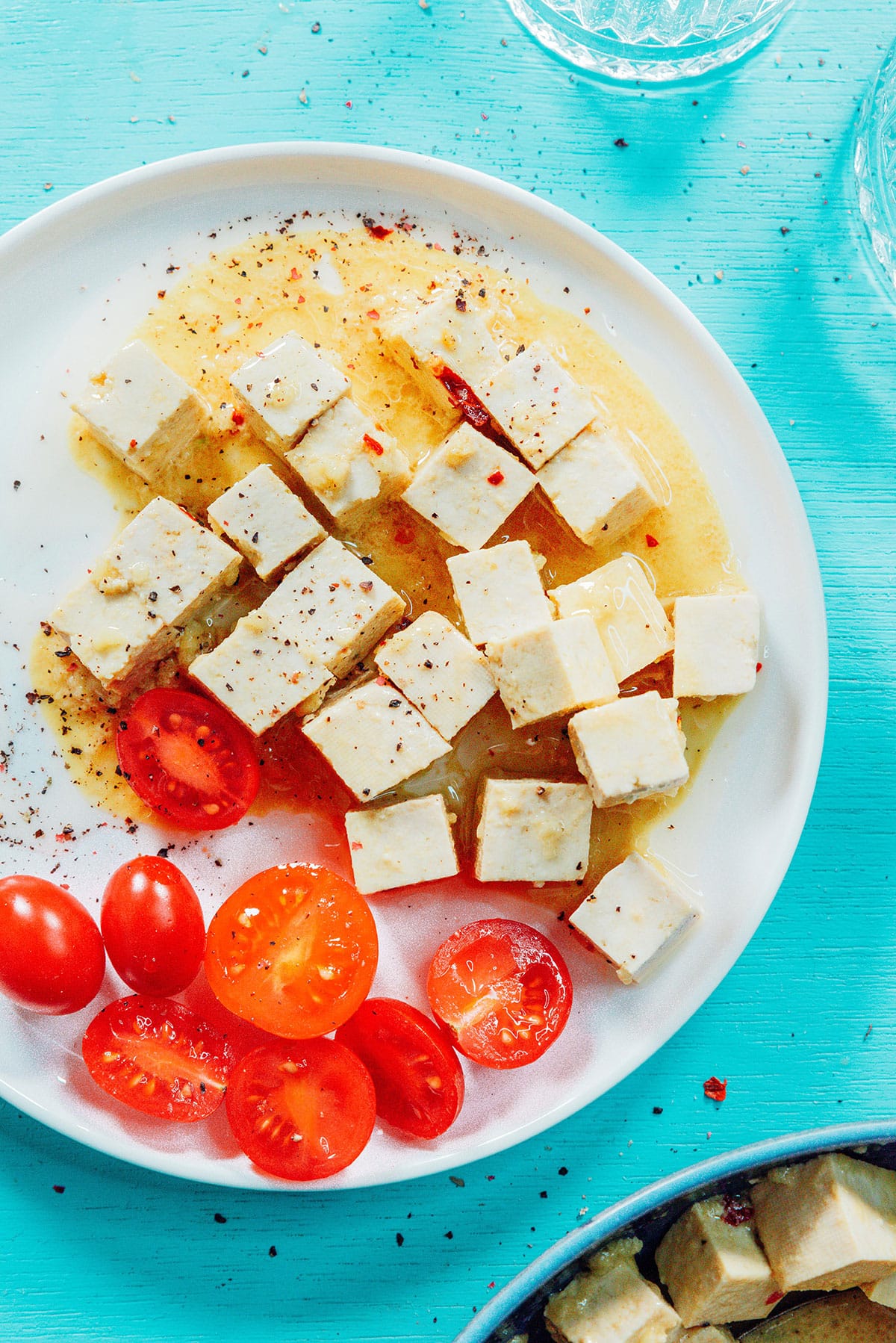 Vegan feta on a plate next to tomatoes.