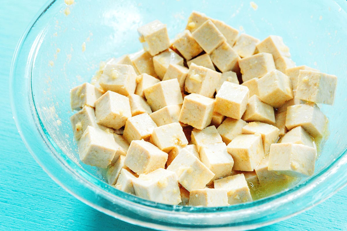tofu in a bowl tossed in marinade.