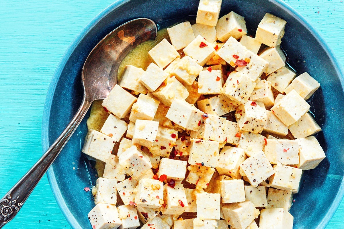 Marinated tofu feta in a bowl topped with red pepper flakes.