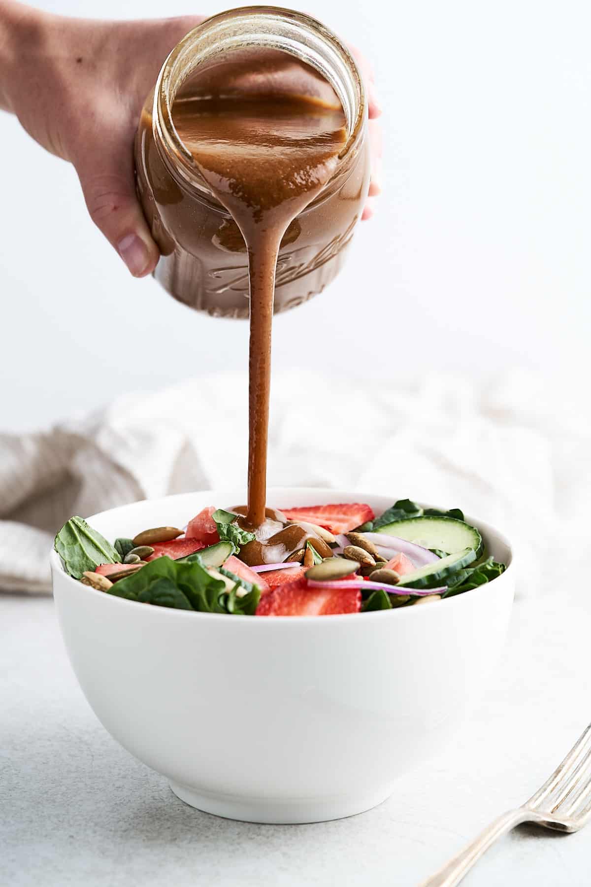 Pouring oil and vinegar dressing over salad.
