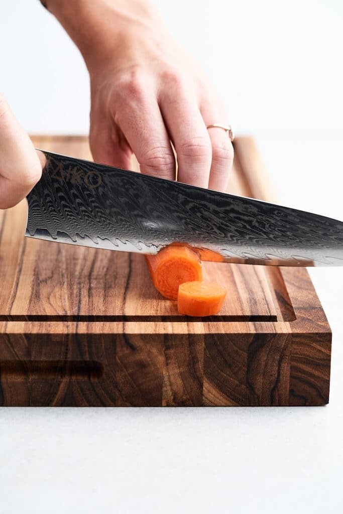 Chef knife cutting a carrot.