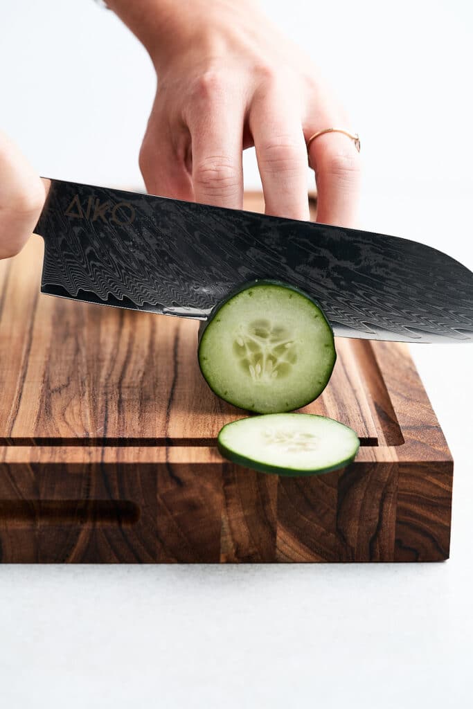 Santoku knife slicing a cucumber.