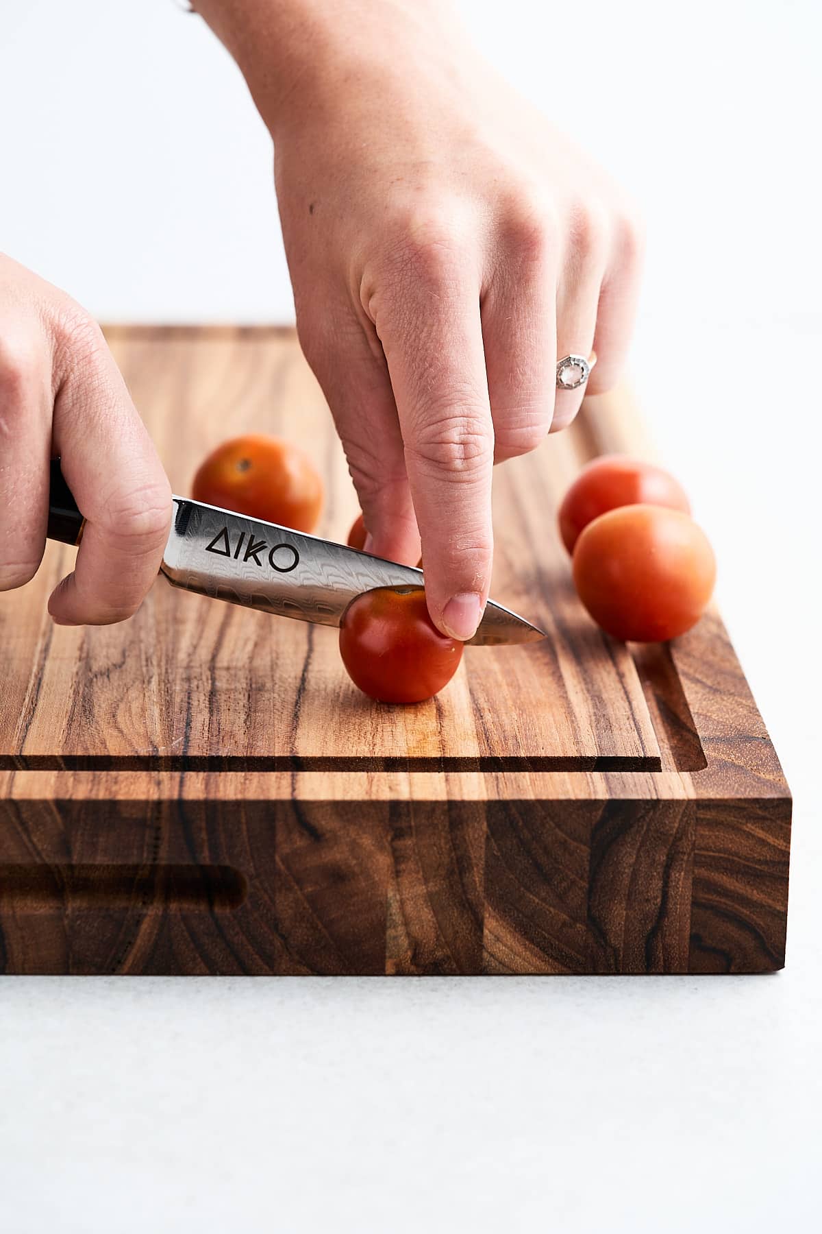 Paring knife slicing a cherry tomato.