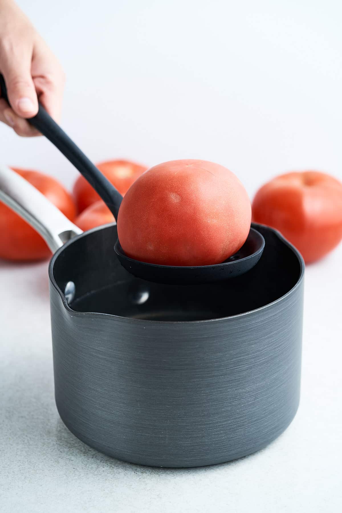 Adding a tomato to a pot of boiling water.