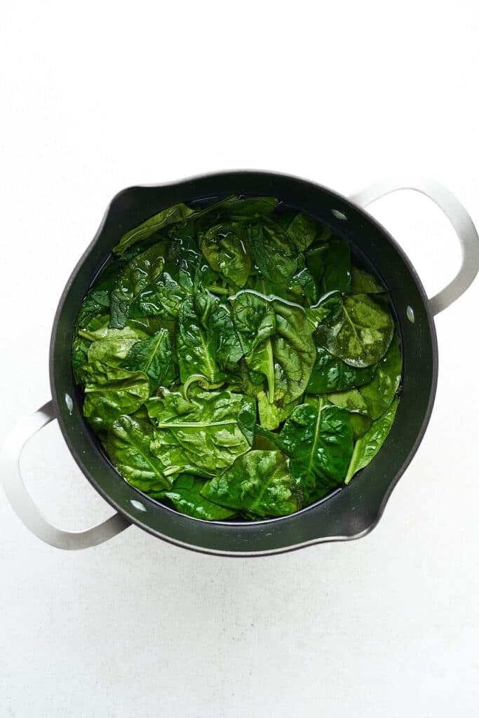 Blanching spinach in a pot.
