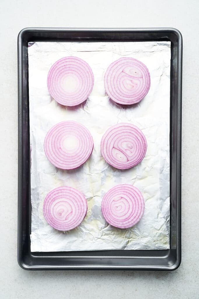 Red onion halves on a pan.