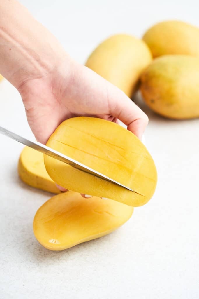 Slicing mango flesh lengthwise.
