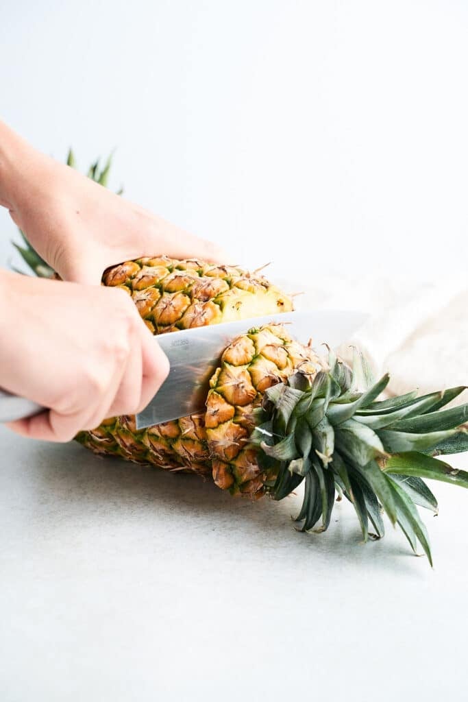 Cutting the top off a pineapple.