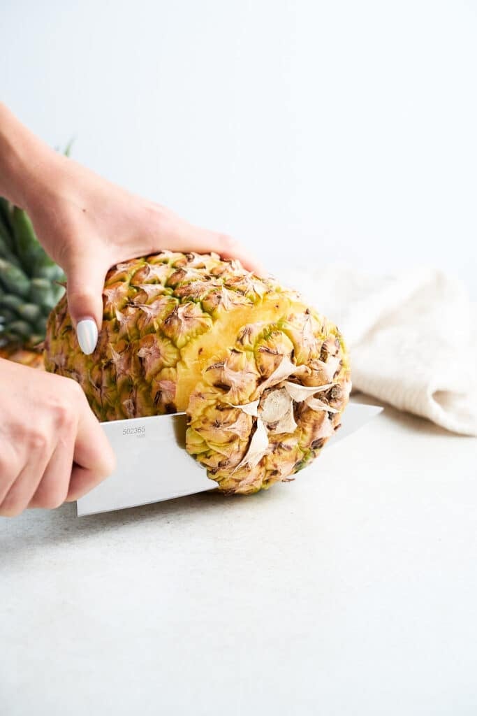 Cutting the bottom off a pineapple.