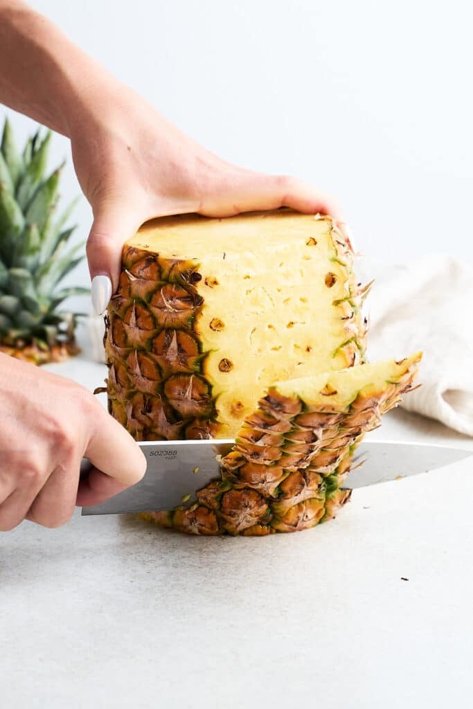 Slicing the skin off a pineapple.