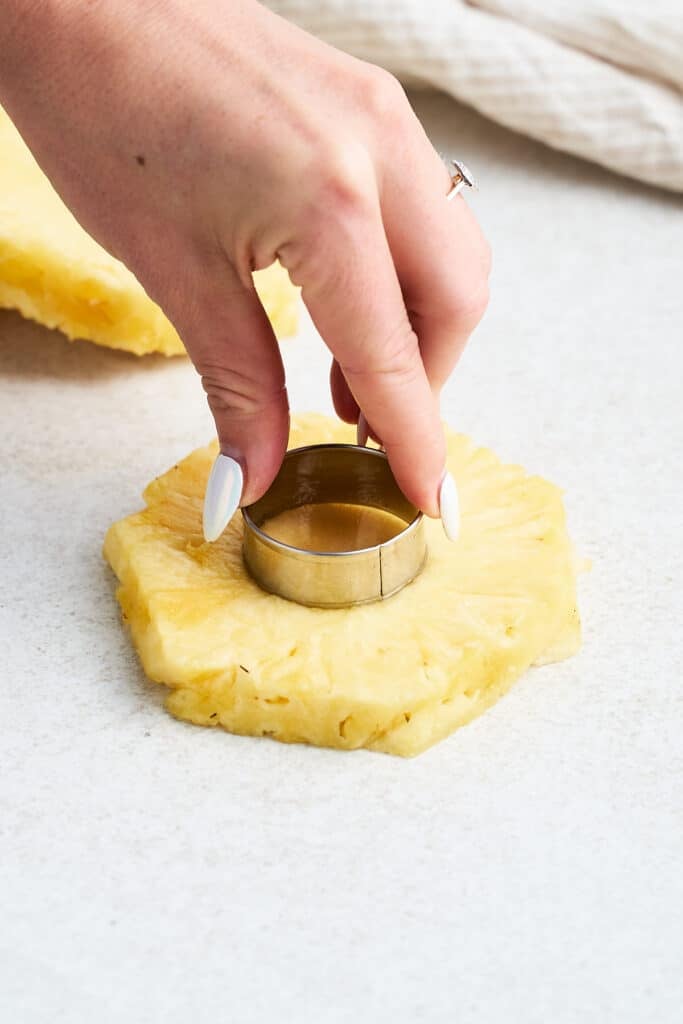 Removing the core from a pineapple ring.