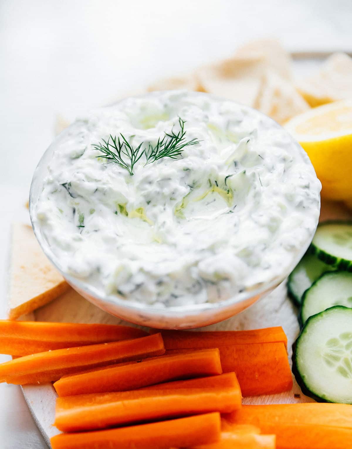 Best tzatziki recipe with pita bread and veggies on a marble table.