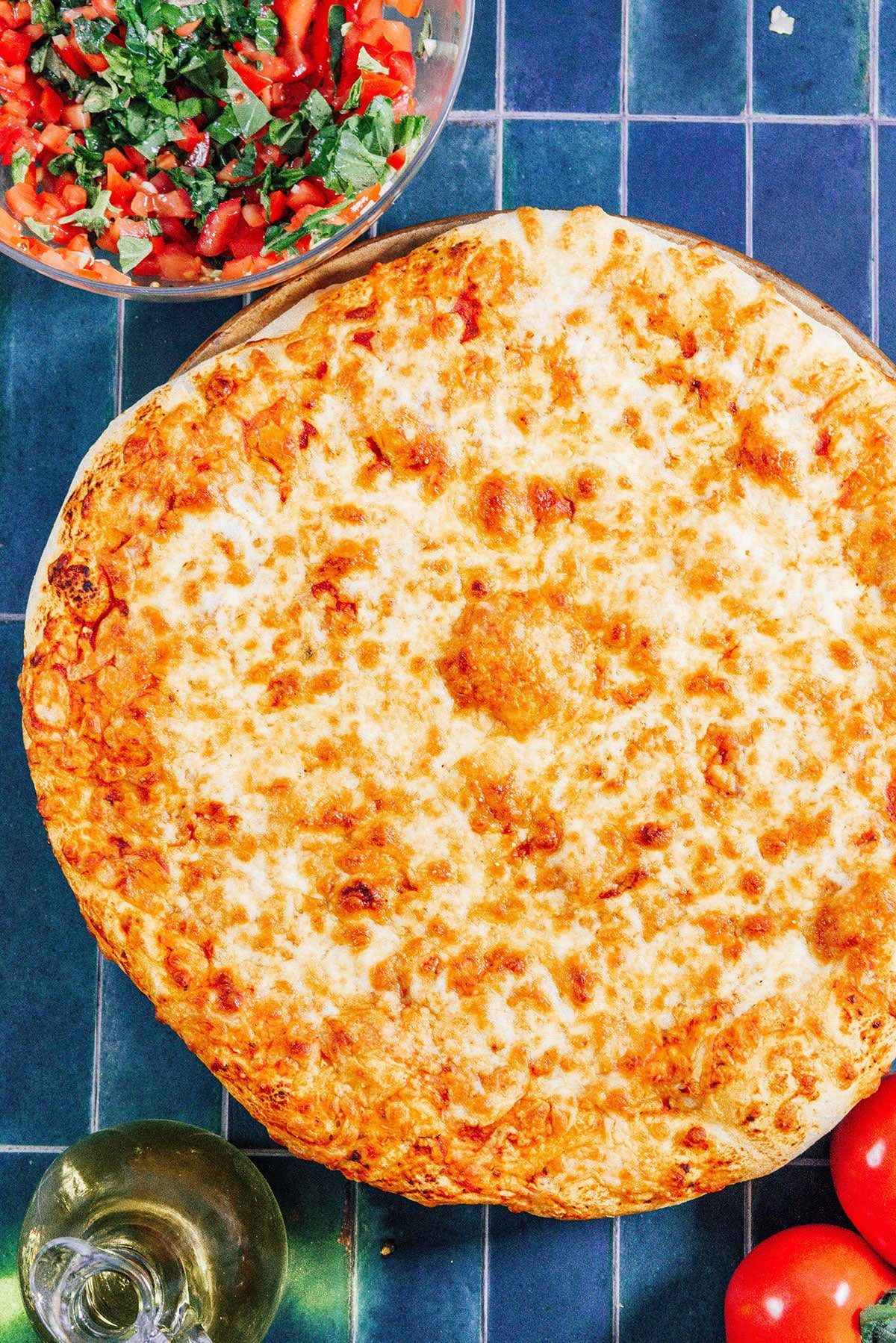 Cheese pizza on a blue tile background.