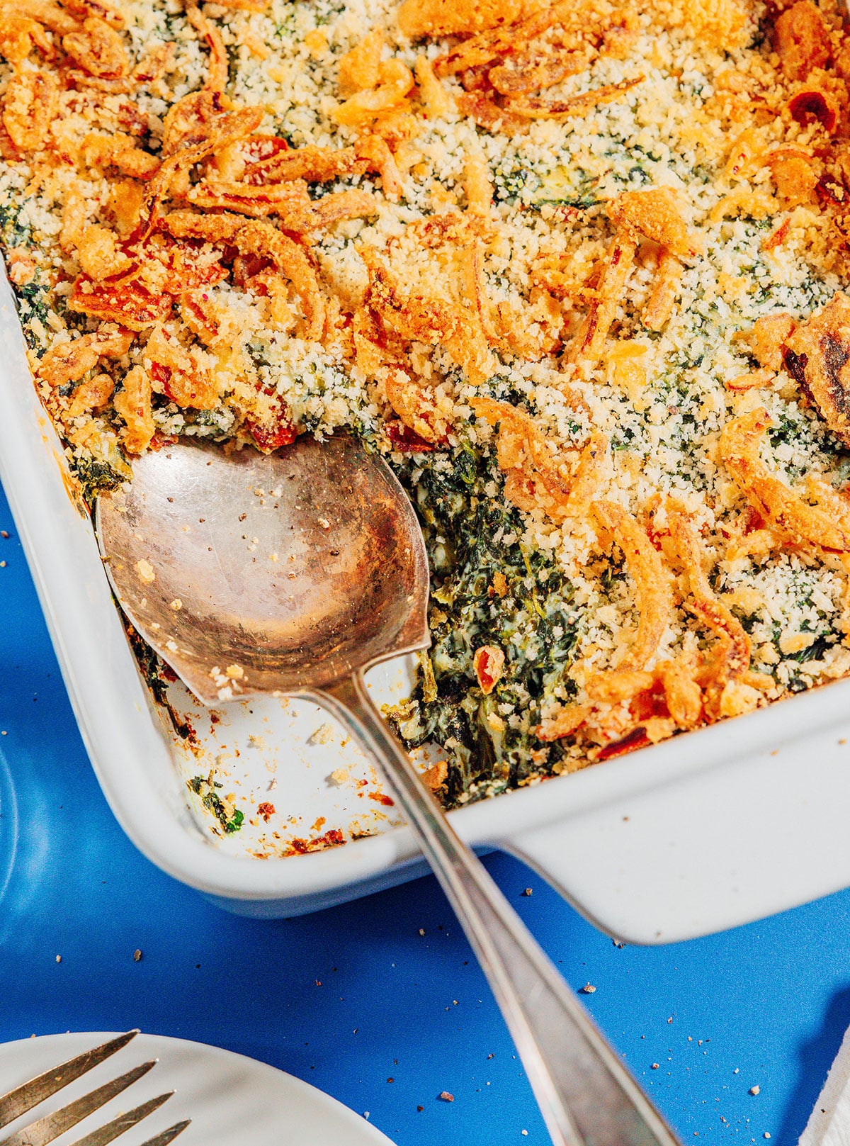 Spinach casserole in a baking dish with a spoon.